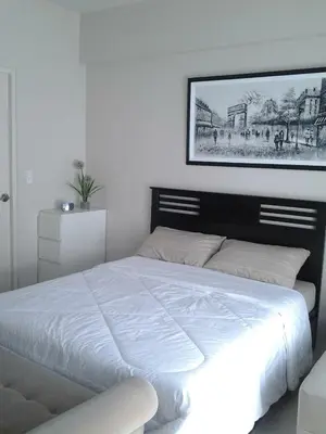 a bedroom with a white bed with a picture on the wall at One Palm Tree Villa CC9N in Manila