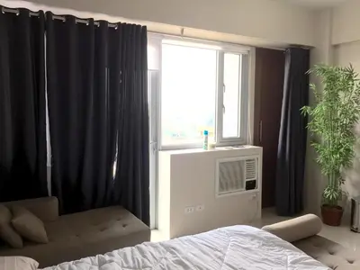 a bedroom with a bed and a window with black curtains at One Palm Tree Villa CC9N in Manila
