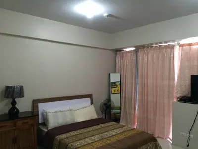 a bedroom with a bed and a television and a window at Love This Place in Manila