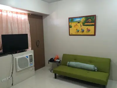 a living room with a green couch and a tv at Love This Place in Manila