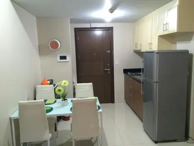 a kitchen with a table with chairs and a refrigerator at Love This Place in Manila