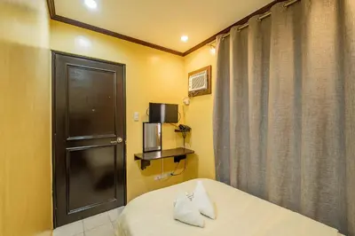 a room with a bed with a door and a window at Hotel Juliano in Manila