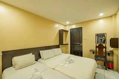 a bedroom with a bed with white sheets and a mirror at Hotel Juliano in Manila