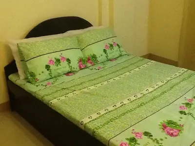 a bed with a green comforter with pink flowers on it at AAM Transient and Guest House in Manila