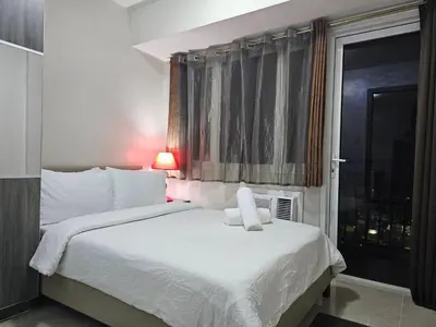 a bedroom with a white bed with a window at Solemare Parksuites Condominium - Condo R Us in Manila