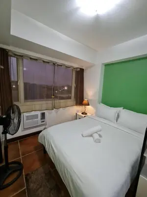 a bedroom with a large white bed and a window at Solemare Parksuites Condominium - Condo R Us in Manila