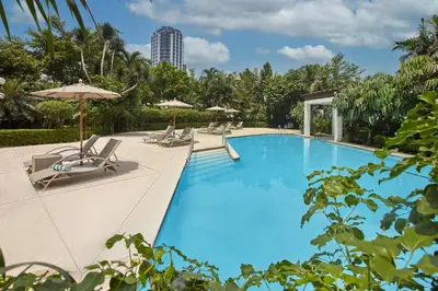 a large blue swimming pool with chairs and umbrellas at Crowne Plaza Manila Galleria by IHG in Manila