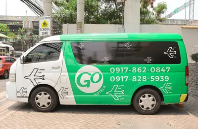 a small green and white van parked on a street at Go Hotels Manila Airport Road in Manila