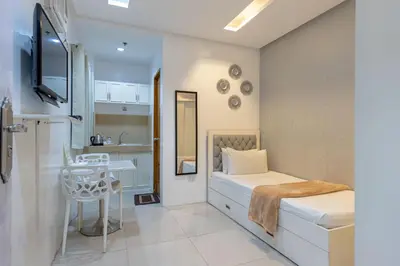 a small room with a bed and a table in it at Baymont Suites & Residences in Manila