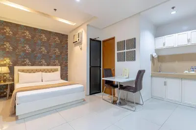 a bedroom with a bed and a desk and a kitchen at Baymont Suites & Residences in Manila