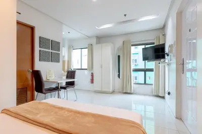 a hotel room with a bed and a table and a television at Baymont Suites & Residences in Manila