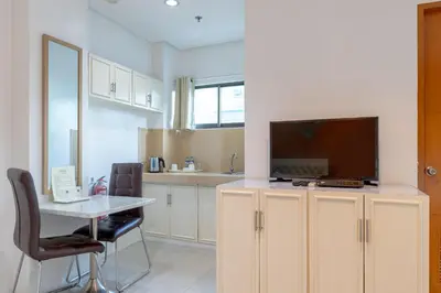 a kitchen with a table and a tv on a cabinet at Baymont Suites & Residences in Manila