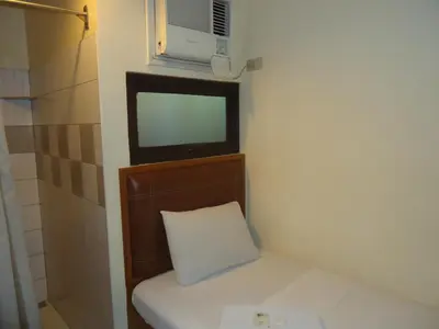 a small bathroom with a toilet with a tv on the wall at Park Bed and Breakfast Hotel Pasay in Manila
