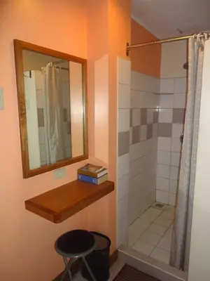 a bathroom with a shower with a mirror and a stool at Park Bed and Breakfast Hotel Pasay in Manila