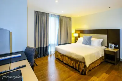 a hotel room with a bed and a flat screen tv at Somerset Alabang Manila in Manila