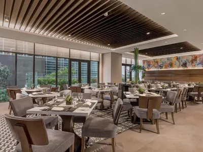 a restaurant with tables and chairs and windows at Somerset Alabang Manila in Manila