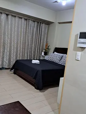 a bedroom with a black bed and a window at Palm Tree Villas by Ann in Manila