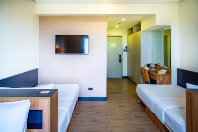 a hotel room with two beds and a television at The Bayleaf Cavite in General Trias