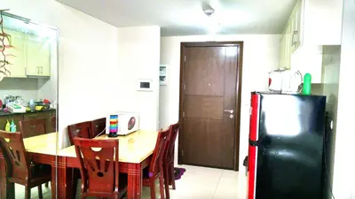 a kitchen with a wooden table and a black refrigerator at 3N Palm Tree Villas in Manila