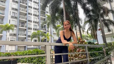 a woman leaning on a fence in front of a building at 3N Palm Tree Villas in Manila