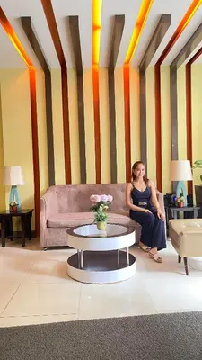 a woman sitting on a couch in a living room at 3N Palm Tree Villas in Manila
