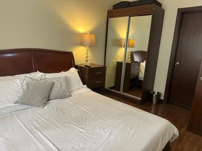 a bedroom with a white bed with a large mirror at Luxury suite next to Shangrila and Westin Hotels in Manila