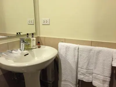 a bathroom with a white sink and towels at Luxury suite next to Shangrila and Westin Hotels in Manila