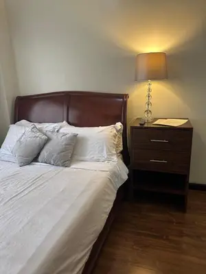 a bedroom with a bed with a lamp and a nightstand at Luxury suite next to Shangrila and Westin Hotels in Manila