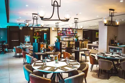 a restaurant with tables and chairs and a bar at Wynwood Hotel in Manila