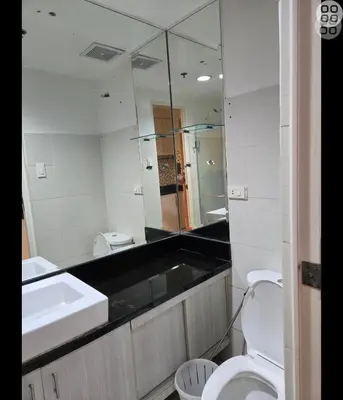 a bathroom with a sink and a toilet and a mirror at FinkSea @ Sea Residences in Manila