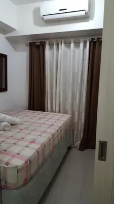 a bedroom with a bed and a window with curtains at FinkSea @ Sea Residences in Manila