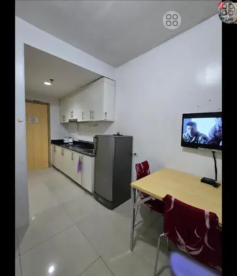 a kitchen with a table and a tv on the wall at FinkSea @ Sea Residences in Manila
