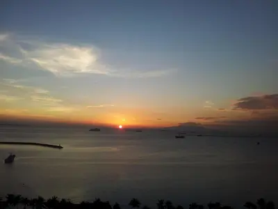 a sunset over the ocean with boats in the water at Baywatch Tower in Manila