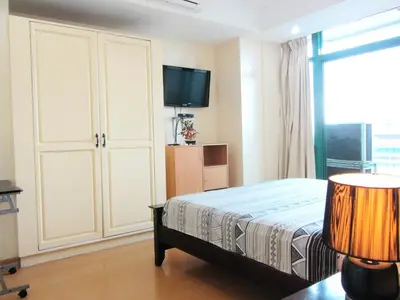 a bedroom with a bed and a flat screen tv at Baywatch Tower in Manila