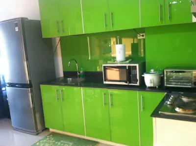 a green kitchen with green cabinets and a refrigerator at Sea Residences MOA-Eric Apartments in Manila