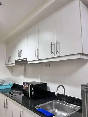 a kitchen with a sink and a microwave at Sea Residences MOA-Eric Apartments in Manila
