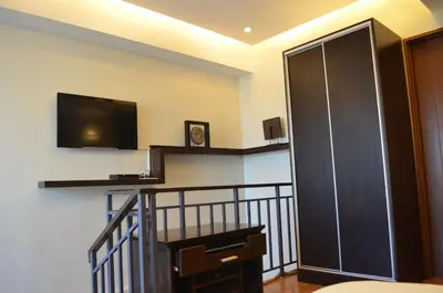 a living room with a tv and a staircase with a flat screen at Eton Parkview in Manila