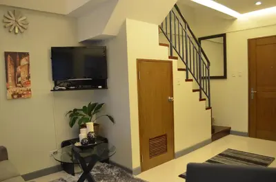 a living room with a staircase and a television at Eton Parkview in Manila