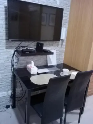 a black table with chairs and a television on a wall at Condo At Shell Residences in Manila