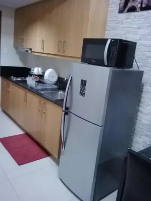 a kitchen with a refrigerator with a microwave on top of it at Condo At Shell Residences in Manila
