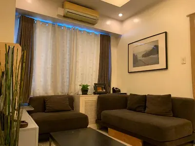 a living room with two couches in front of a window at Eastwood Residence Above Eastwood Mall in Manila