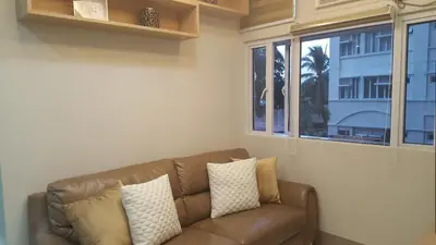 a brown couch in a living room with windows at Suntrust Parkview Apartment in Manila