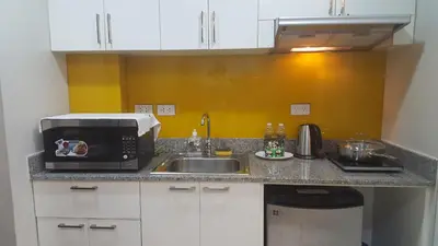 a kitchen counter with a sink and a microwave at Suntrust Parkview Apartment in Manila