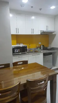 a kitchen with white cabinets and a wooden table at Suntrust Parkview Apartment in Manila