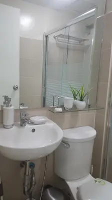 a bathroom with a sink and a toilet and a mirror at Suntrust Parkview Apartment in Manila