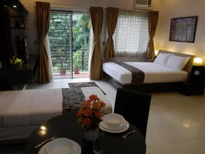 a hotel room with two beds and a table with flowers on it at New Manila Suites in Manila