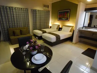 a hotel room with a bed and a table and a room at New Manila Suites in Manila