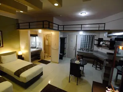 a bedroom with a bed and a desk in a room at New Manila Suites in Manila