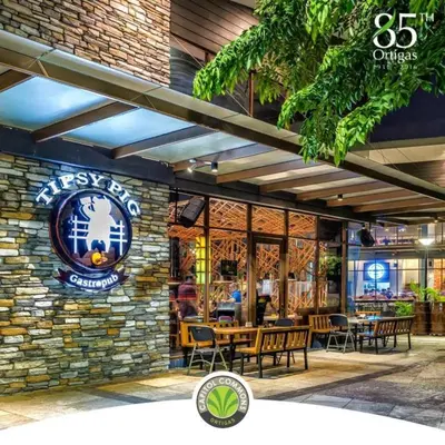 a restaurant with a stone wall and tables and chairs at Ortigas Budget Hotel - Kapitolyo in Manila