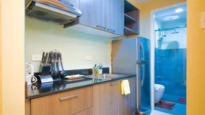 a small kitchen with a sink and a shower at Currency Serviced Suites in Manila